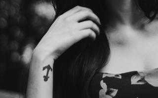 Mão da mulher com tatuagem de âncora no pulso