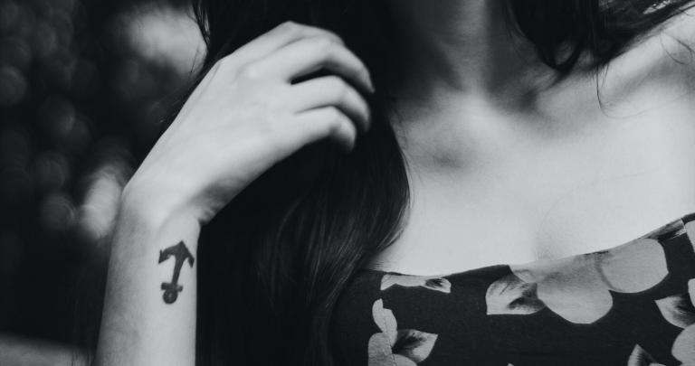 Mano de mujer con tatuaje de un ancla en la muñeca