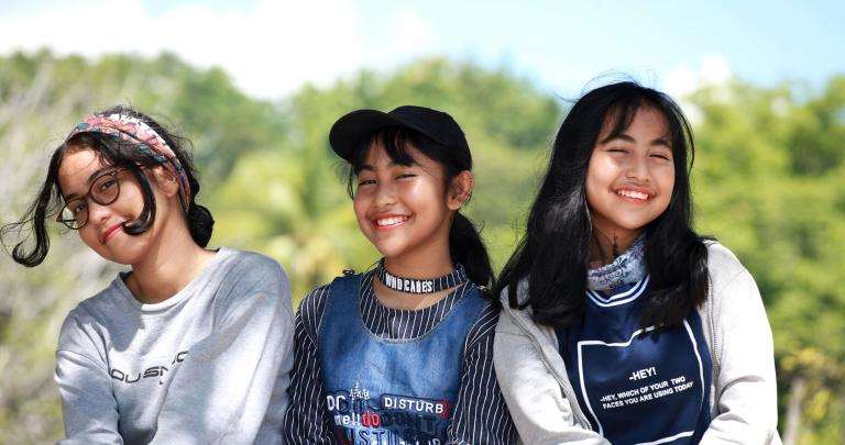 Trois filles souriantes assises l'une à côté de l'autre