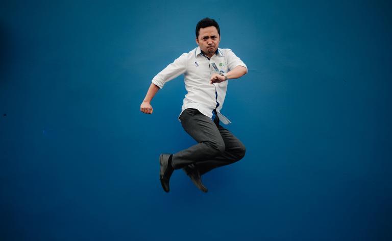 Homme sautant en hauteur sur fond bleu