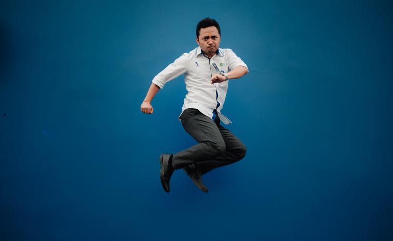 Hombre saltando alto sobre fondo azul